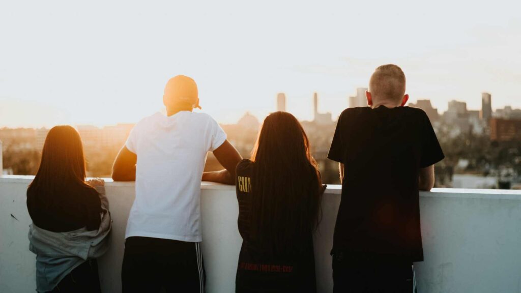 Four young people on a rooftop looking at the sunrise