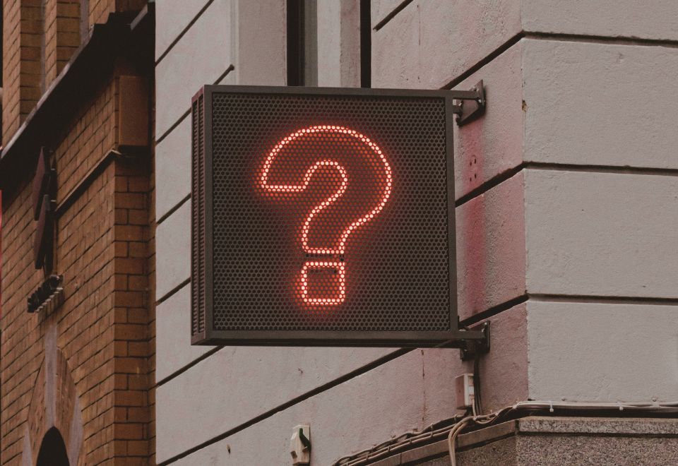 A neon sign of a question mark on the side of a building